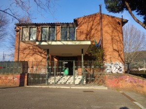 Edificio della Scuola dell'Infanzia il Campino. Edificio in mattoncini rossi con cancellata e gradini per l'ingresso.